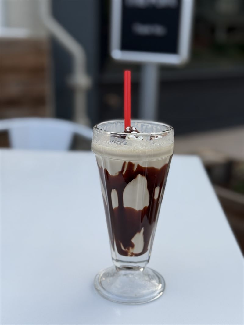 An ice cream drink layered with chocolate in a tall soda-fountain glass